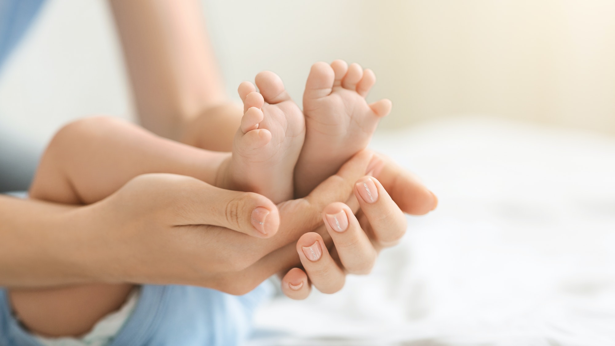 Tiny feet of a newborn baby in caring mother's hands